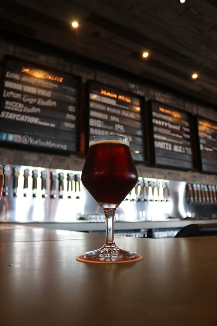 Close-up of dark beer in a glass inside a trendy bar with menu boards and taps.