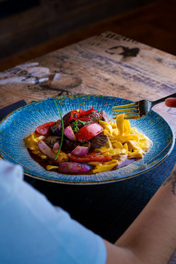 Colorful gourmet pasta with vegetables served on a rustic table setting.