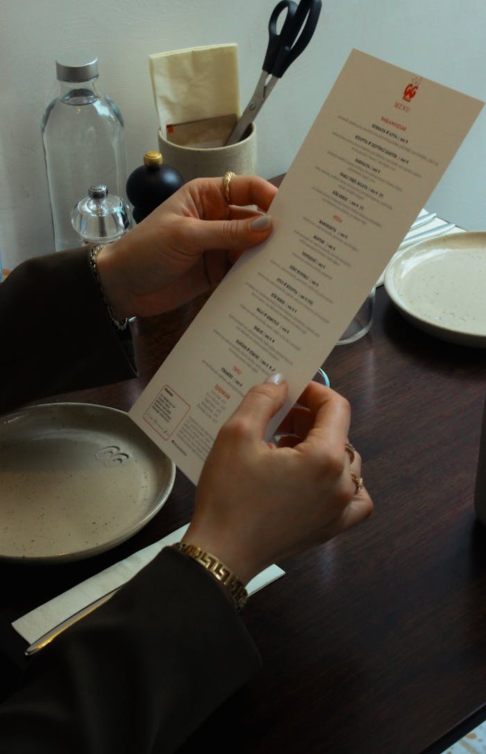 The Art of Drawing Readers In: Your attractive post title goes here Hands holding a menu at a restaurant table, suggesting dining ambiance.
