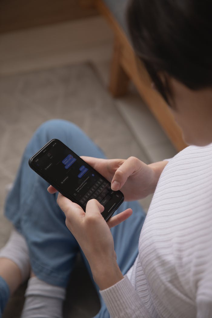 A woman using a smartphone to text, captured from above, indoors setting.